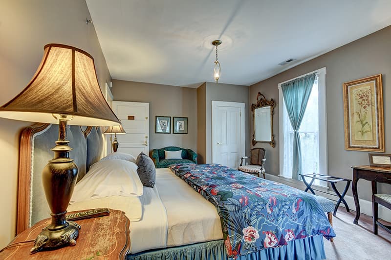 Cozy bedroom featuring a large bed, floral bedding, a lamp, and elegant decor.