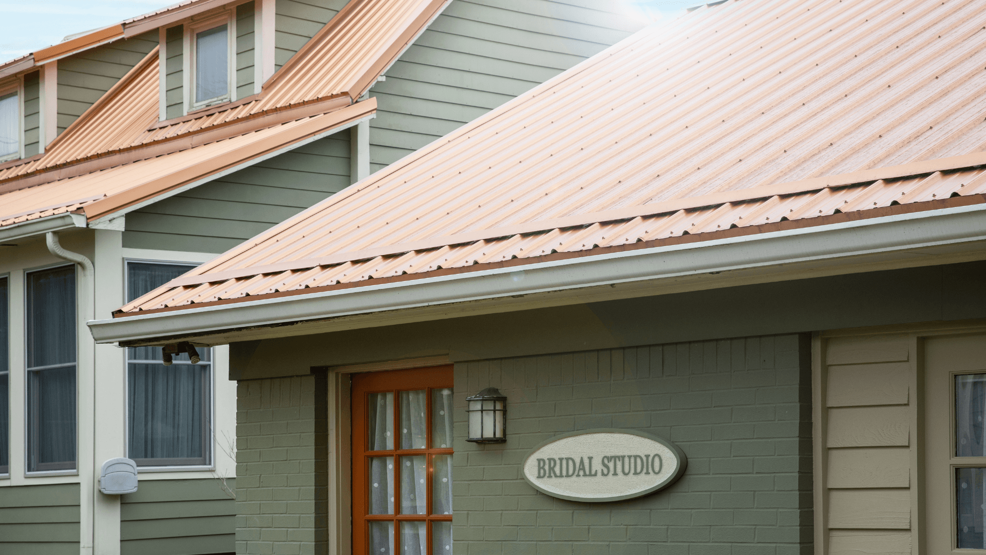 A close-up of a bridal studio with a sign and orange metal roofing.