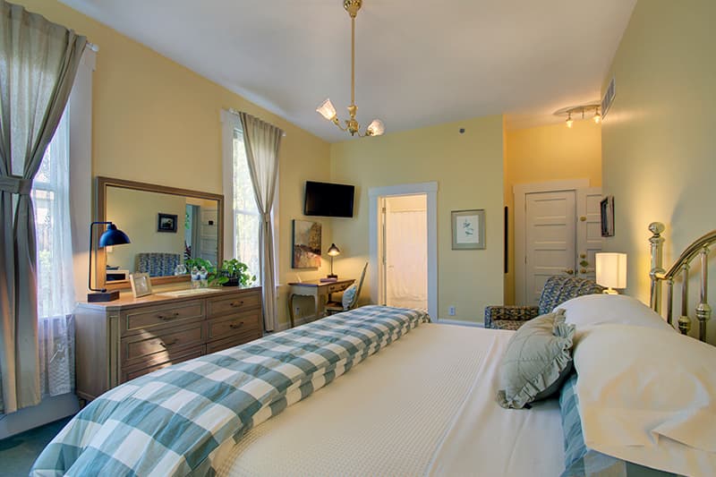 Cozy bedroom with yellow walls, a plaid bedspread, and a decorative dresser.