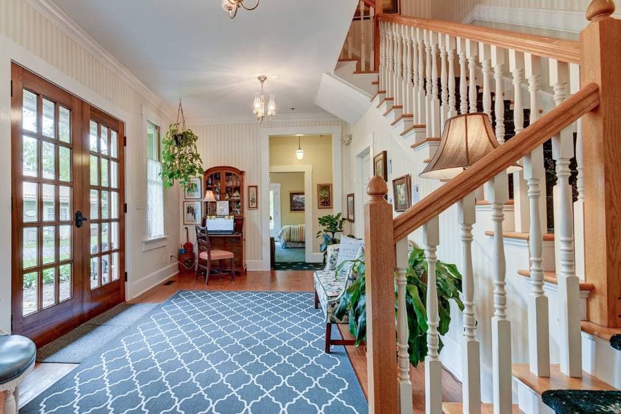 A welcoming foyer with a staircase, patterned rug, and wooden accents.