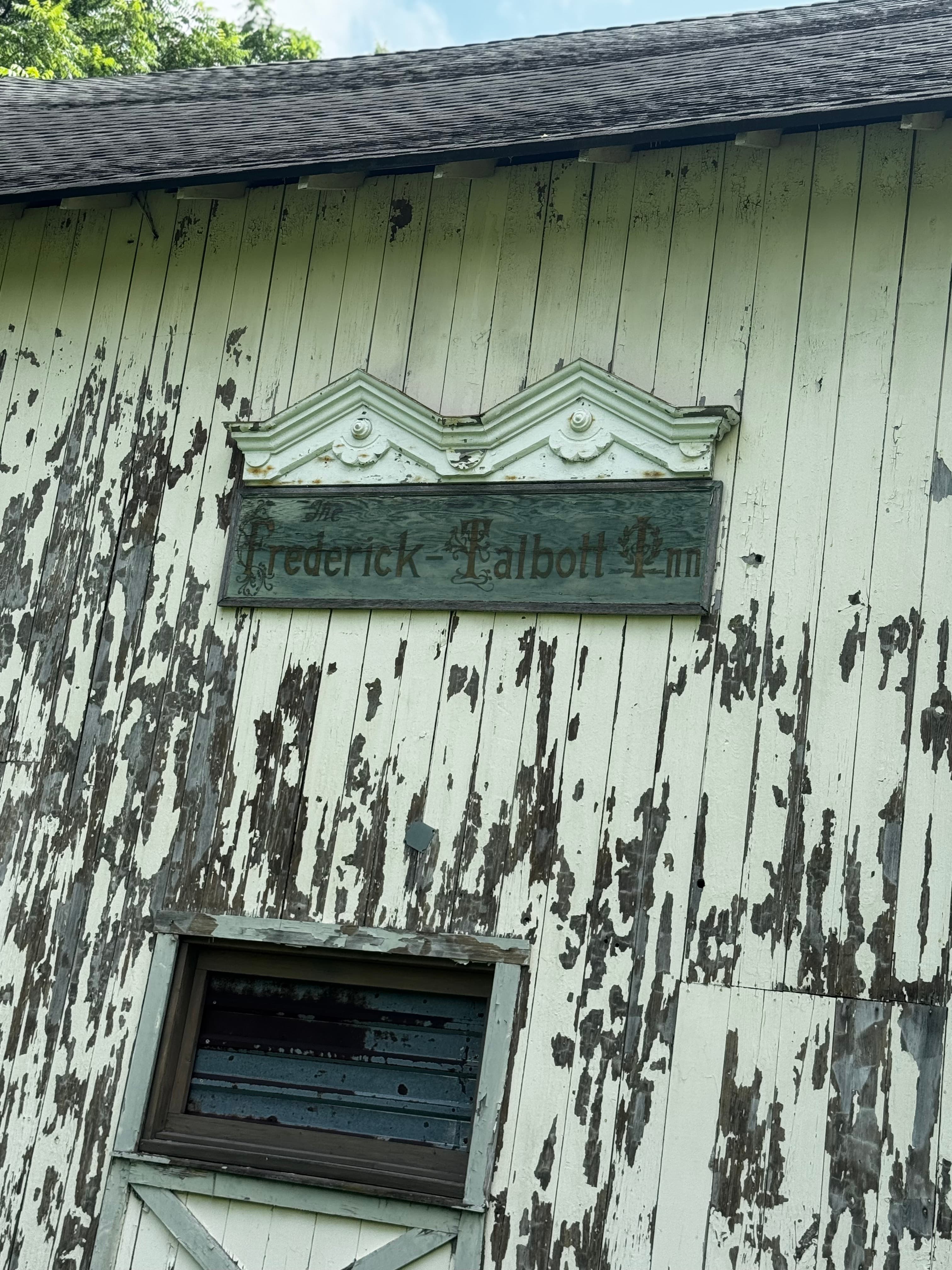 A weathered sign reading "Frederick Talbott Inn" on a dilapidated wooden building.