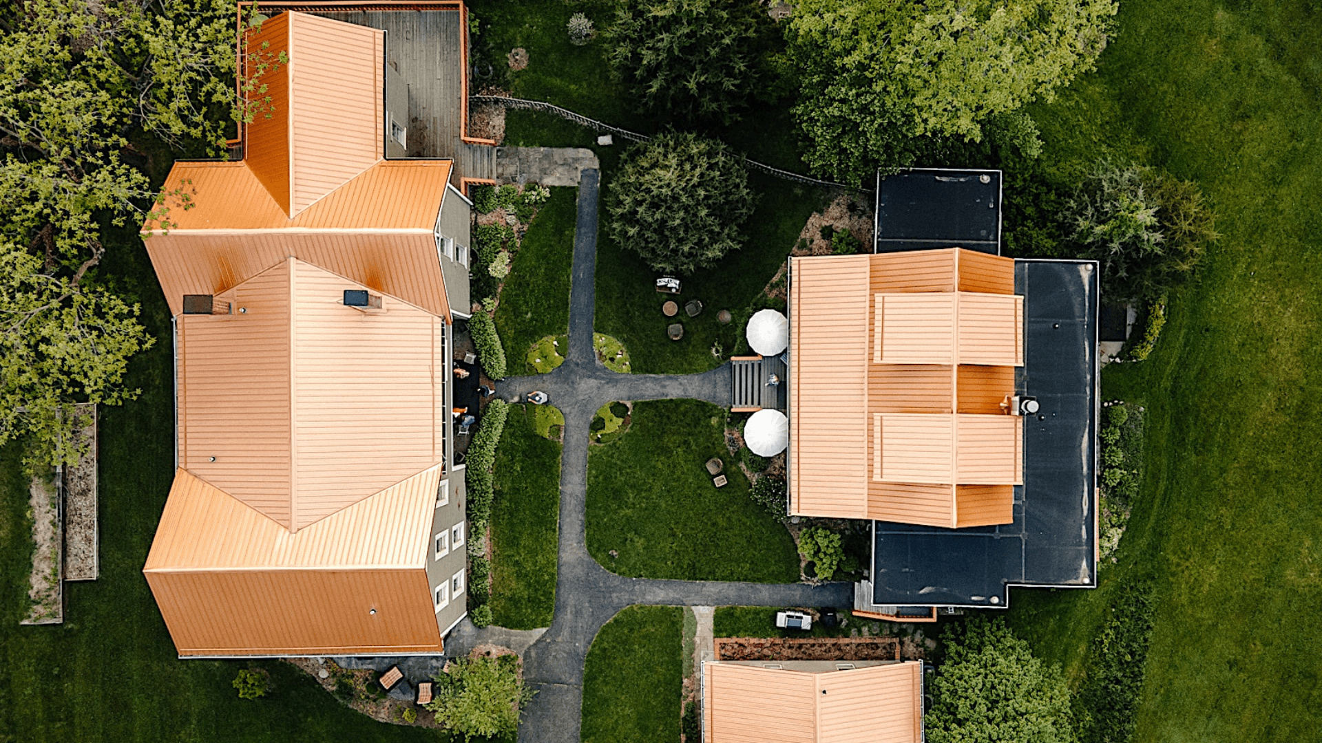 Aerial view of two buildings with orange roofs surrounded by green lawns and pathways.
