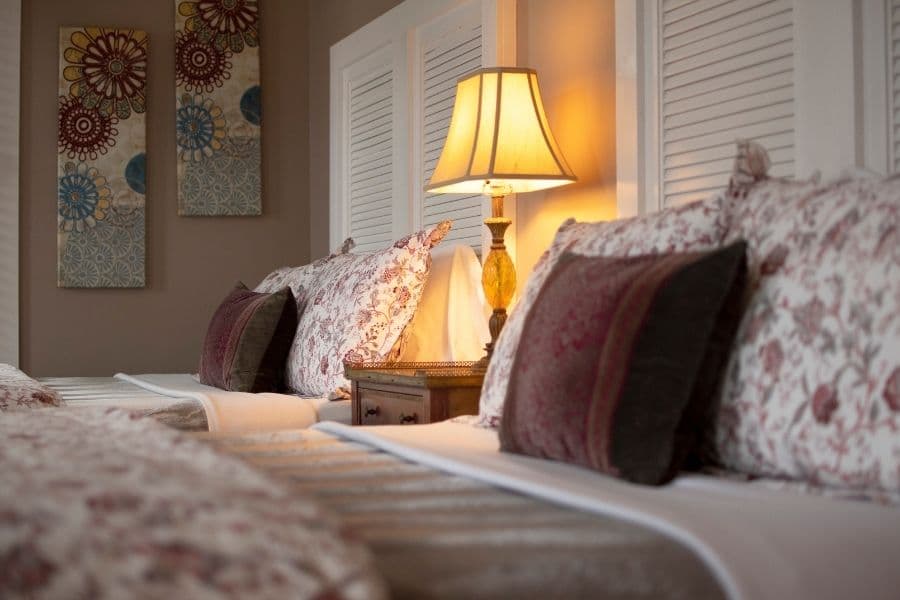 A cozy bedroom featuring two beds adorned with floral-patterned bedding and a decorative lamp.