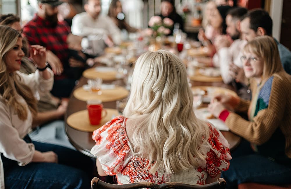 A group of people gathered around a dining table, enjoying food and conversation.