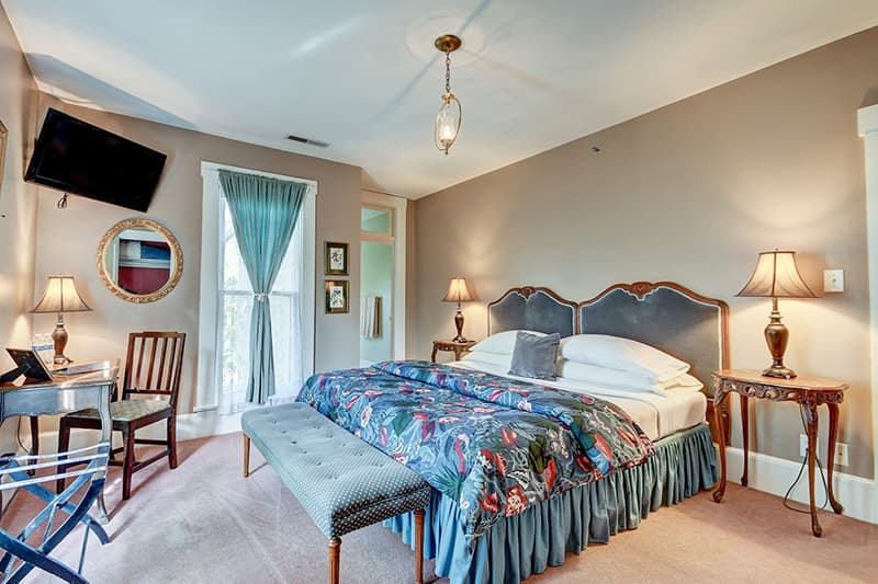 Cozy bedroom featuring a floral-patterned bedspread, bedside lamps, and a desk by the window.