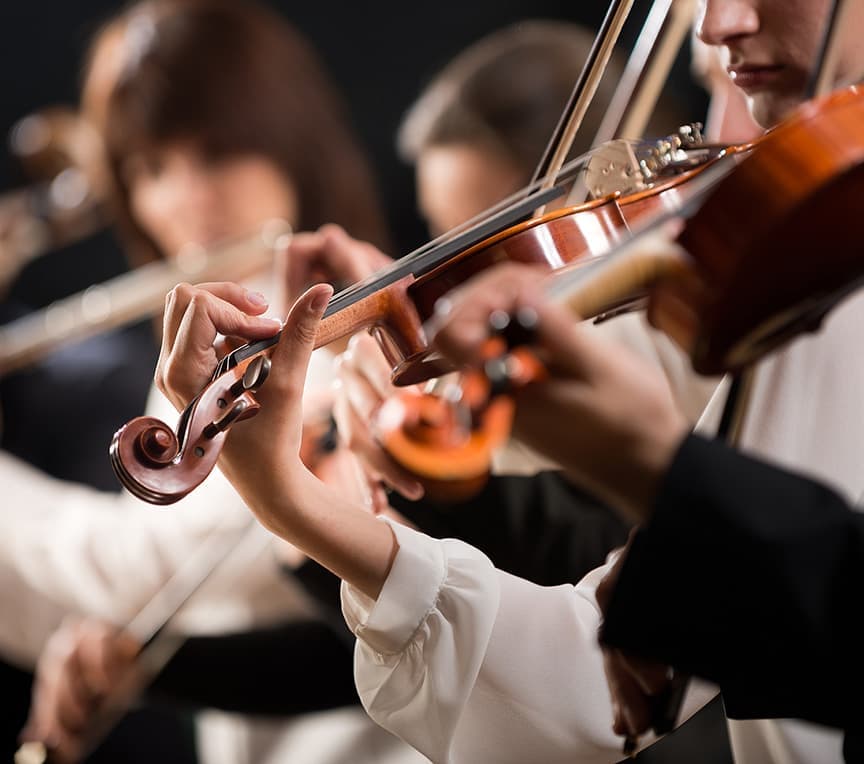 Close-up of musicians playing violins in an orchestra.