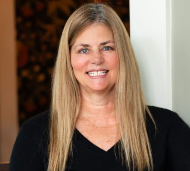 A smiling woman with long hair wearing a black sweater.