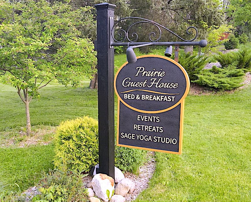 A sign for Prairie Guest House Bed & Breakfast listing events, retreats, and Sage Yoga Studio.