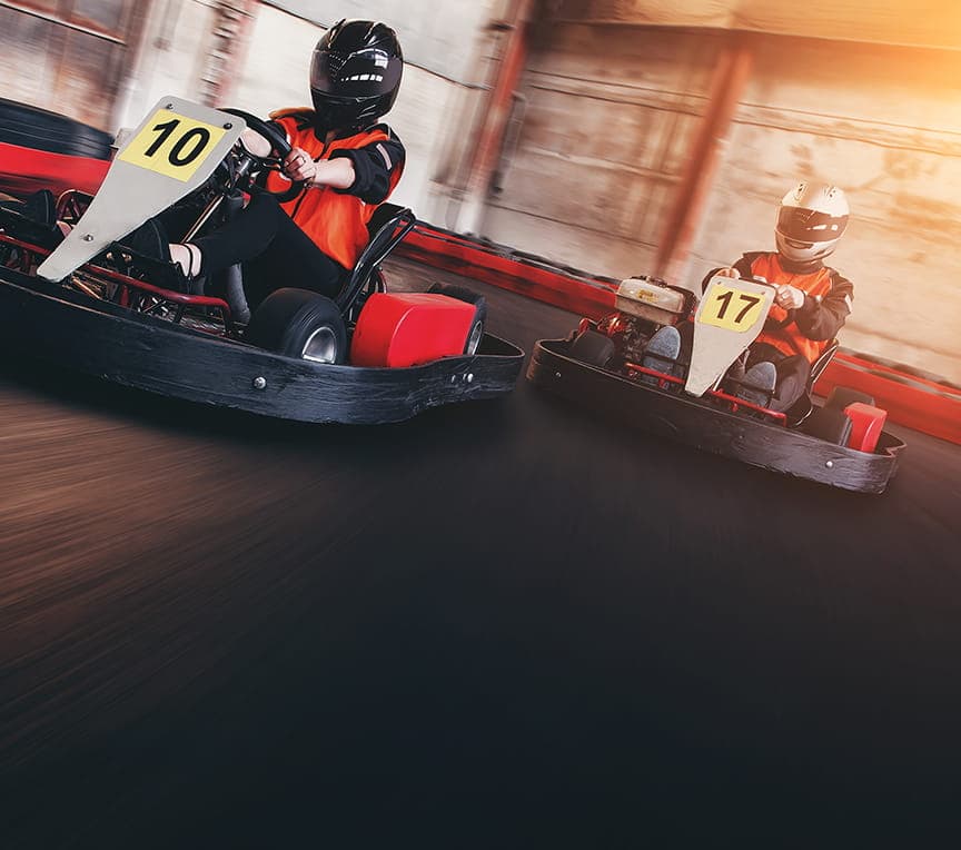 Two go-karts race around a track, labeled 10 and 17, with drivers wearing helmets.