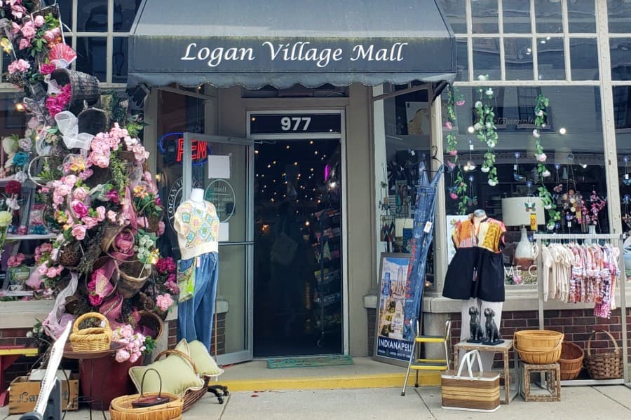 Entrance of Logan Village Mall adorned with flowers and various clothing displays.