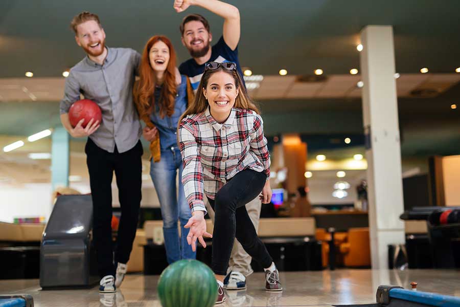 A group of four friends enjoys bowling at a bowling alley.