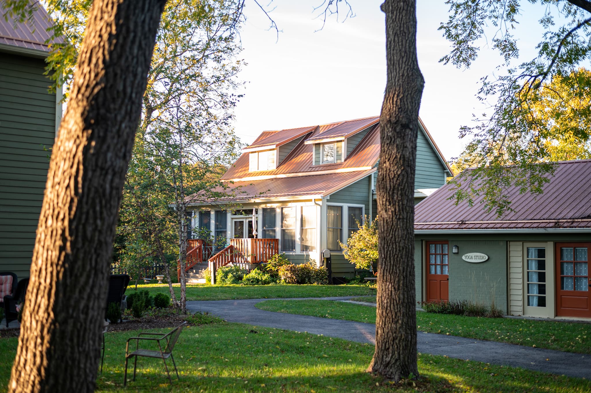 A charming house with a red roof and surrounded by green trees and a well-maintained lawn.