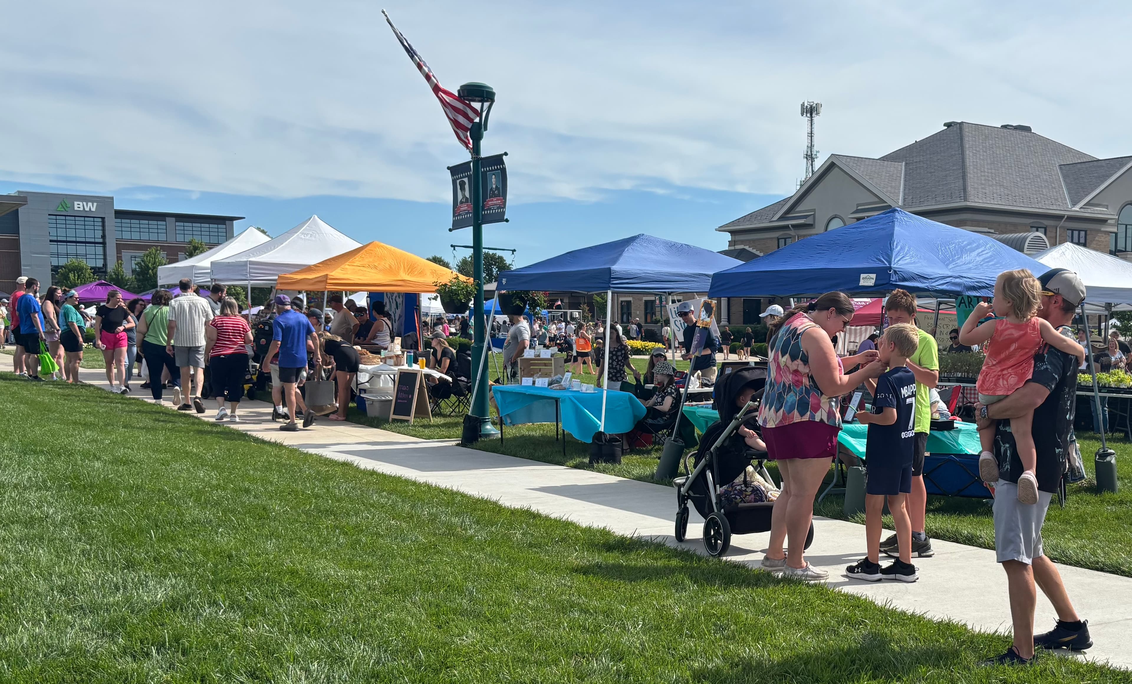 A lively outdoor market scene with colorful tents, vendors, and families enjoying the day. A lively outdoor market scene with colorful tents, vendors, and families enjoying the day.
