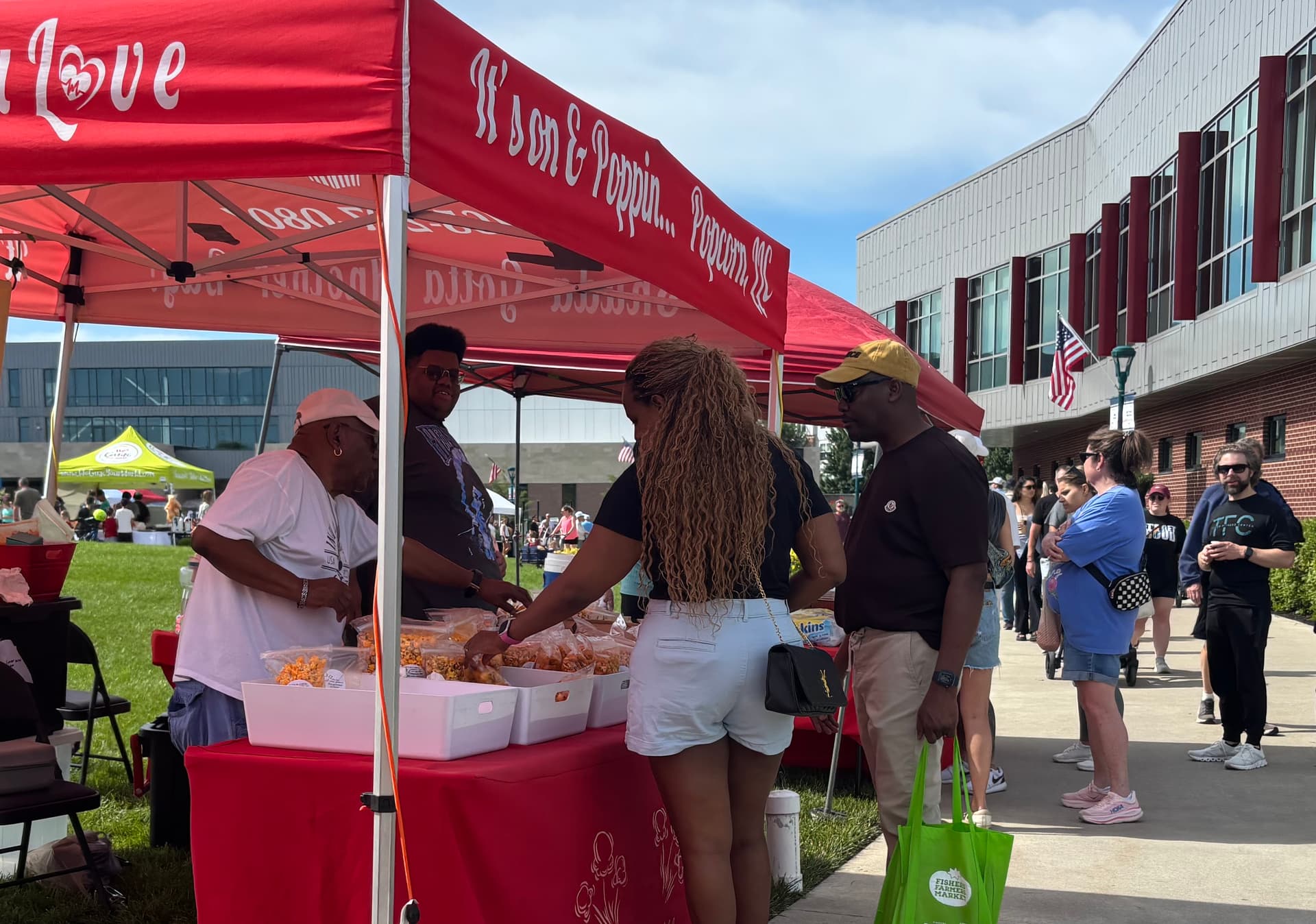 Customers buying popcorn from local vendors at the Fishers Farmers Market in Indiana.