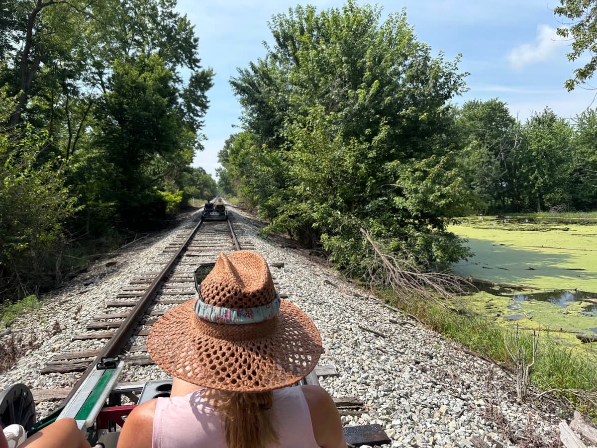 View of a railbike on the railroad track beside a green pond and trees.