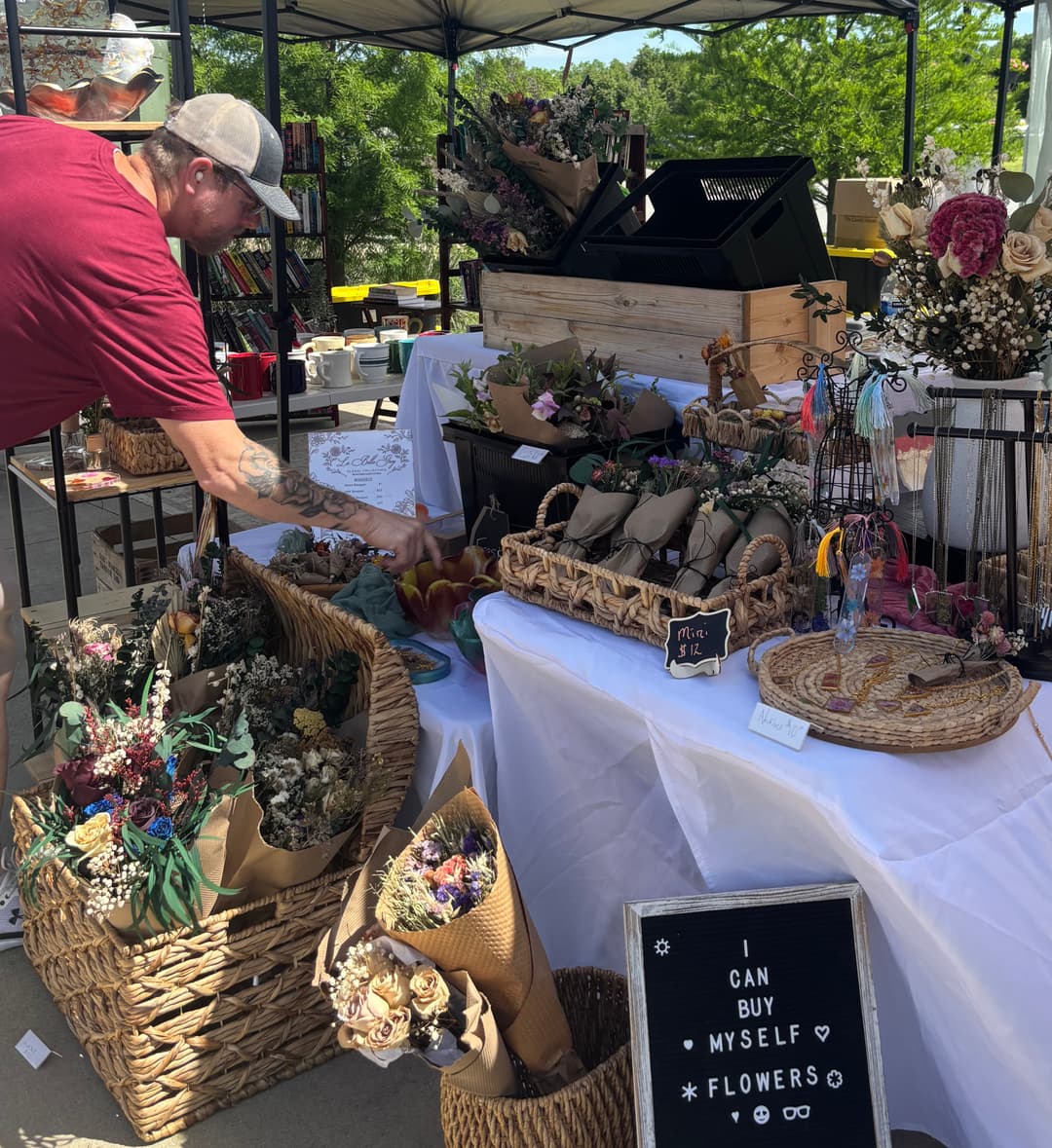 Customer viewing the beautiful flower bouquets and arrangements made by a local vendor at the Noblesville Farmers Market in Indiana.